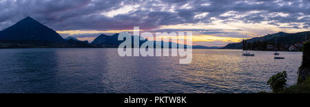 Ein spektakuläres Panorama Landschaft wie die Sonne über Interlaken, Schweiz. Wolken gegen die Berge mit der Reflexion auf dem See gedrückt wird. Stockfoto