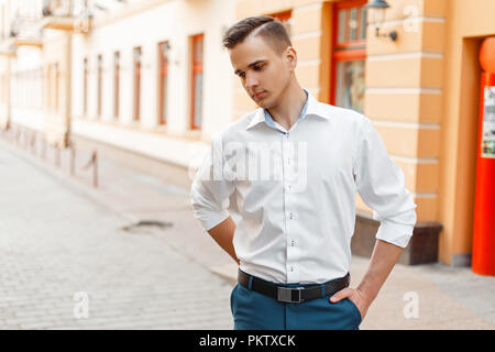 Schöne stilvolle Mann in einem weißen elegantes Shirt und blauen Hosen in der Stadt Stockfoto