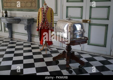 Schwarze und weiße checker Fliesenboden in der Burg mit einem Dummy in vollem Dining regalia und eine silberne Schüssel auf einem Tablett Stockfoto