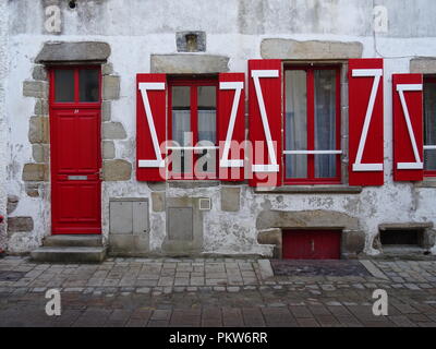 Hellen roten Fensterläden auf einem typischen Stein Strand Haus an der Westküste von Frankreich durch eine Straße mit Kopfsteinpflaster Stockfoto