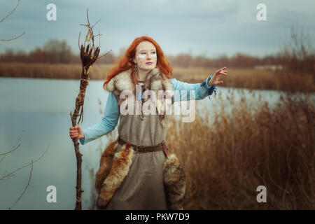 Heidnische Frau ist ein Schamane mit einem Stab in den Händen. Stockfoto