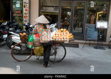 Eine ländliche Frau verkauft Obst in einer alten Straße in Hanoi, Vietnam. Stockfoto