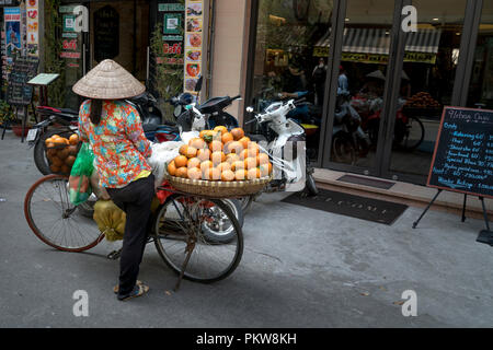 Eine ländliche Frau verkauft Obst in einer alten Straße in Hanoi, Vietnam. Stockfoto