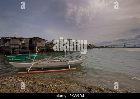 Kleine Fischerboote vor hausbesetzer, Pfahlbauten, Twilight Zone, slum Gegend am Meer Stockfoto