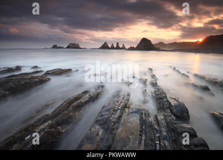 Die Sonne über den Felsen von Gueirua Strand, in Asturien, Spanien Stockfoto