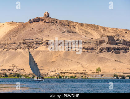 Qubbet el-Hawa, gewölbte hilltop Grab und alten Gräbern in der Wüste Cliff, West Bank, mit einer Feluke segeln Boot auf dem Fluss Nil, Assuan, Ägypten, Afrika Stockfoto