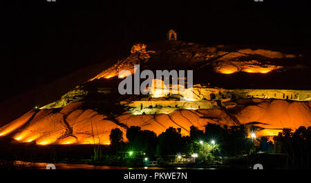 Nacht Blick über den Nil Qubbet el-Hawa Grab zu Hügel, Kuppel der Winde, und alten Hügel Gräber beleuchtet, Assuan, Ägypten, Afrika Stockfoto