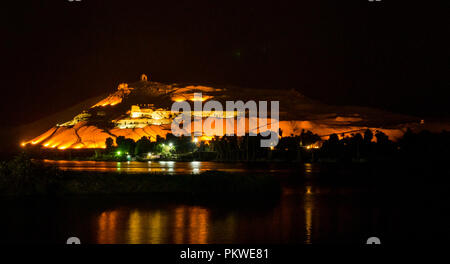 Nacht Blick über den Nil mit lichtreflexionen Qubbet el-Hawa Grab zu Hügel, Kuppel der Winde, und alten Hügel Gräber, Assuan, Ägypten, Afrika Stockfoto