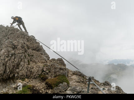 Junge attraktive männliche Bergsteiger auf einem steil und ausgesetzt Klettersteig in Alta Badia in Südtirol in den italienischen Dolomiten Stockfoto