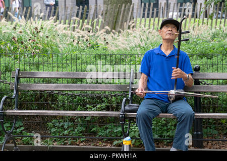 Eine ältere die chinesisch-amerikanische spielt die ehru auf einer Bank in Washington Square Park in Manhattan, New York City. Stockfoto
