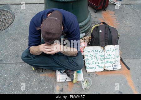 Ein zerknirschter junger Mann an der 42nd Street und Sixth Avenue mit einem Schild um Spenden mit einer bewegenden Schild, er ist nicht unsichtbar. Stockfoto