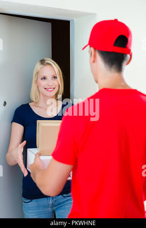 Junge Frau empfangen Paket von Delivery Man Stockfoto