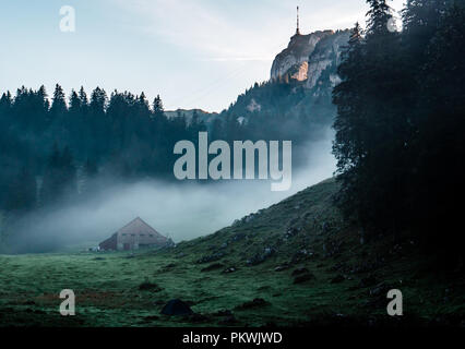 Geheimnisvolle Hütte und Zelt während der morgendlichen Sonnenaufgang mit Nebel, Schweiz Stockfoto