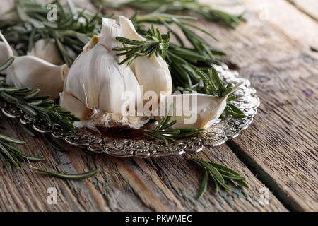 Rosmarin und Knoblauch an einem alten Holztisch. Stockfoto