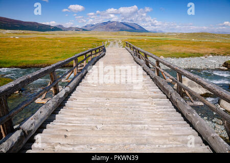 Hölzerne Brücke über einen Fluss mit weit entfernten Bergkette im Hintergrund, Altai Gebirge, der westlichen Mongolei Stockfoto