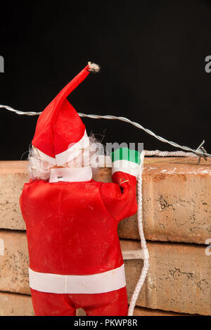 Santa Versuch, die Wand ein zuwanderungskonzept zu klettern Stockfoto