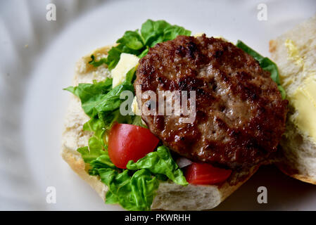 Home food Vorbereitung. Hausgemachtes Rindfleisch Burger, Pommes und Salat zubereitet in einer eigenen Küche. Bild zeigt Salat, Salat, Käse, Tomaten und Pommes Frites. Stockfoto