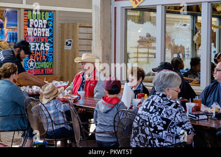 Staycation Idee. Familie Texan genießt das Essen am Tisch im Freien in Fort Worth Stock Yards. East Exchange Avenue, Fort Worth, Texas. Horizontal Stockfoto