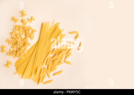 Verschiedene verschiedene Roh rohe Nudeln auf Rosa pastell Hintergrund. Italienische Pasta: Penne, Farfalle, Spaghetti. Stockfoto