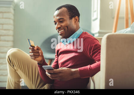 Happy afro-amerikanische Mann Eingabe der Kartennummer Stockfoto