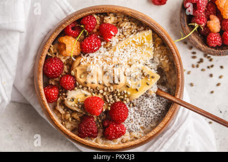 Haferflocken Porridge mit Chia Samen, Beeren, Erdnussbutter und Hanf samen in Houten. Vegan gesunde Ernährung Konzept. Stockfoto