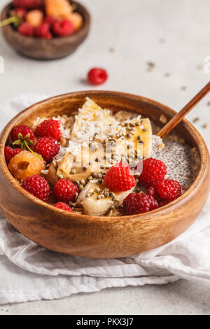 Haferflocken Porridge mit Chia Samen, Beeren, Erdnussbutter und Hanf samen in Houten. Vegan gesunde Ernährung Konzept. Stockfoto