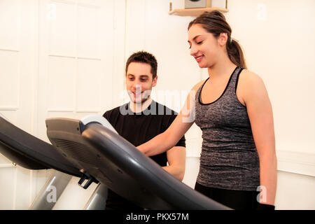 Maschine Laufband Riemen in der Turnhalle. Glückliche junge Frau und Fitness persönlicher Lehrer mit der Zwischenablage arbeiten auf Laufband im Fitnessstudio. Sport. Stockfoto