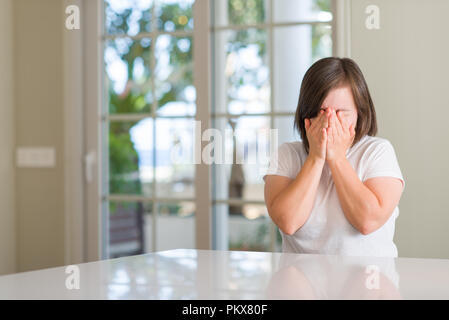 Down Syndrom Frau zu Hause mit traurigen Gesichtsausdruck das Gesicht mit den Händen und weinte. Depression Konzept. Stockfoto