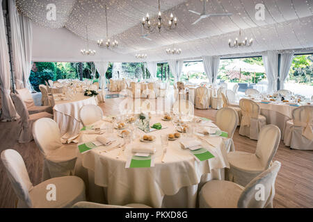 Hochzeit Veranstaltungsort in einer großen Marquis mit eleganten formale weiße Tabelle Einstellungen und Blick auf einen Garten Stockfoto