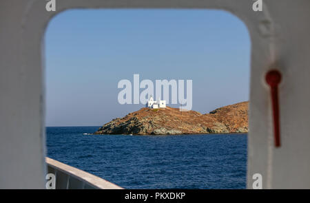 Blick aus der Schiff Tür der Leuchtturm und Agios Nikolaos Kirche auf felsigen Land. Kea, Tzia Insel, Griechenland. Und blauer Himmel. Stockfoto