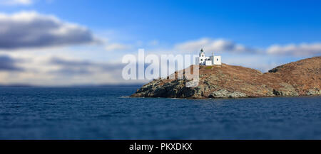 Leuchtturm und Agios Nikolaos Kirche auf felsigen Land. Kea, Tzia der sonnigen Insel, Griechenland. Blur bewölkter Himmel Hintergrund, Banner. Stockfoto