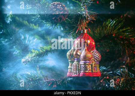 Rot glänzend Dekoration Weihnachten Kugeln Kreml mit Haus in violett-roten Rauch, auf einem Weihnachtsbaum Hintergrund. Konzept eines modernen Weihnachten c Stockfoto