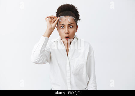 Du hast was. Portrait von schüttelte intensive Afrikanisch-amerikanische Frau zu sehen, unglaublich und furchtbar Durcheinander, die Gläser, falten Lippen und runzelte die Stirn, kann nicht verstehen, was passiert ist, schockiert Stockfoto