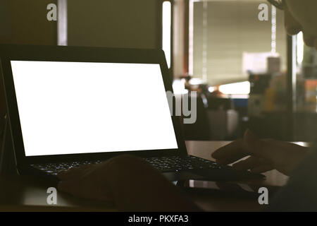 Hand tippen auf Laptop Tastatur angezeigte weißen Hintergrund. PC auf eine Tabelle in einem Büroraum. Stockfoto