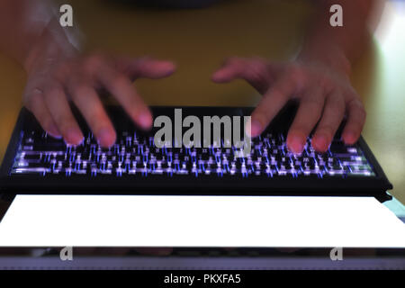 Hand tippen auf Laptop Tastatur angezeigte weißen Hintergrund. PC auf eine Tabelle in einem Büroraum. Stockfoto