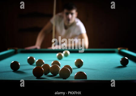 Ein Mann mit einem Bart spielt eine große Billard. Partei in einem 12-Fuß-Pool Stockfoto