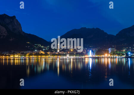 Nachtansicht von Lecco am Comer See mit den Bergen im Hintergrund, Italien wider Stockfoto