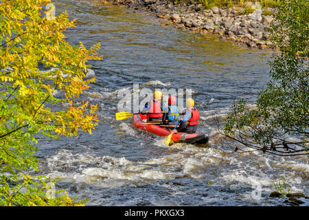 RIVER SPEY SCHOTTLAND HERBSTLICHE BÄUME UND Kanu oder Floß MIT DREI PERSONEN AUF EINEM WEISSEN WASSER Stockfoto