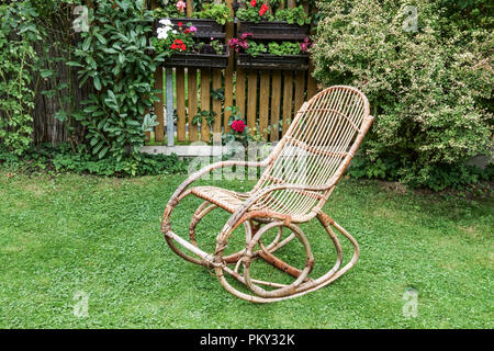 Immer noch leben mit dem alten Rattan Schaukelstuhl im Garten Stockfoto