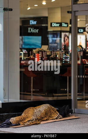 Obdachlosen mit Leopard skin Cover im Shop Eingang, Oxford Street, London, England, Großbritannien Stockfoto