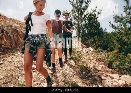 Freunde wandern Sie ein robustes hügeliges Gelände. Mann mit zwei weiblichen Freunde gehen auf einem felsigen Weg in einem Land Seite Lage. Stockfoto