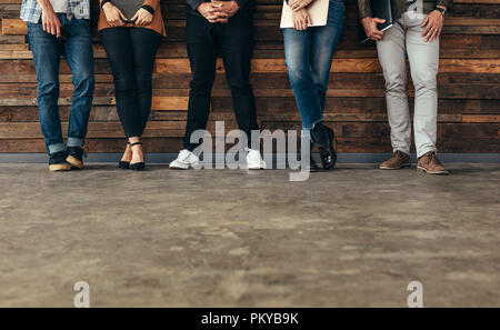 Gruppe von Menschen gegen die Wand lehnt, bevor ein Job Interview mit Ordnern in die Hände in den Warteraum. 7/8 shot der Beine von Menschen in ständigen Stockfoto