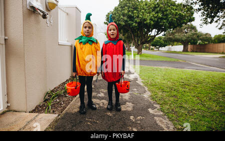 Junge Mädchen in Halloween Kostüm vor einem Haus mit halloween Schaufeln für Trick bereit oder Behandlung. Kinder in Kürbis Kostüme Trick-or-tr Stockfoto