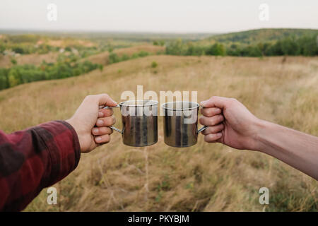 Zwei Hände halten Metall touristische Kappen in schöner Natur. Stockfoto