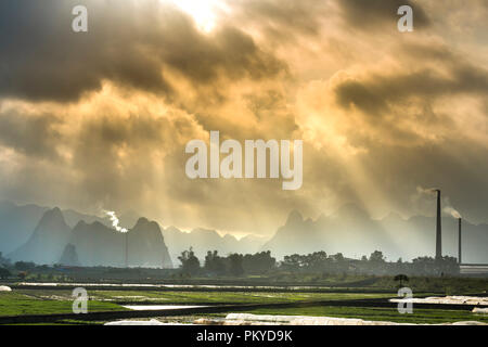 Ländliche Landschaft mit fantasievollen Sonnenlicht, das Reisfeld, die Fabrik, das weit ist das Gebirge Stockfoto