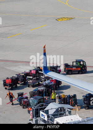 Ein Passagierflugzeug wird am Zürcher Flughafen Kloten geladen. Beschäftigte Arbeitnehmer, Gepäckwagen und Trolleys neben einem Flugzeug. Stockfoto