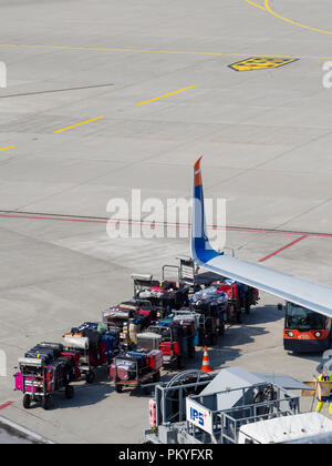 Ein Passagierflugzeug wird am Zürcher Flughafen Kloten geladen. Beschäftigte Arbeitnehmer, Gepäckwagen und Trolleys neben einem Flugzeug. Stockfoto