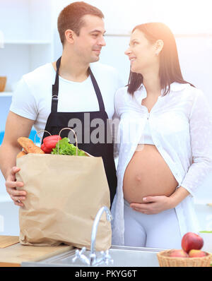 Mann und seine schwangere Frau sind Kämmen durch die Pack, stehen in der Küche Stockfoto