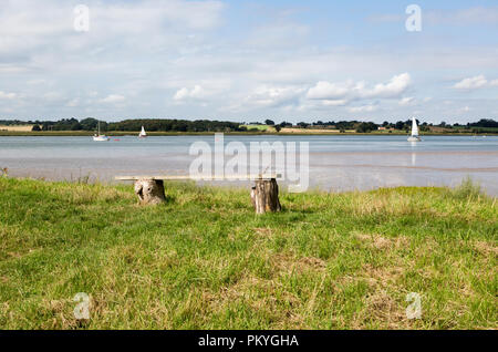 Sommer Querformat der Sitzbank mit Blick auf Segelboote auf der Mündung des Flusses Deben, Sutton, Suffolk, England, Großbritannien Stockfoto