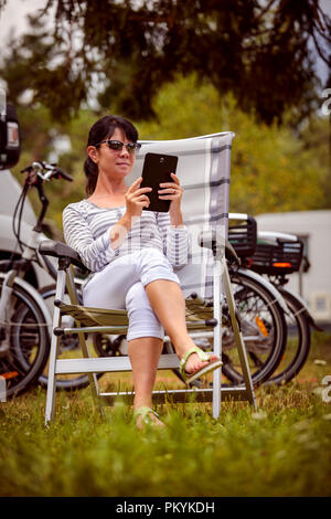 Frau mit Blick auf die Tafel in der Nähe des Camping. Caravan Auto Urlaub. Familie Urlaub Reisen, Urlaub im Reisemobil RV. Wi-fi Verbindung Informatio Stockfoto